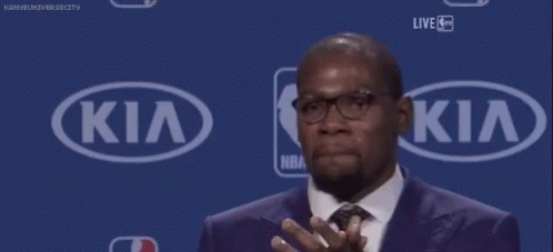 A Man In A Suit And Tie Is Clapping In Front Of A Kia Sign . GIF