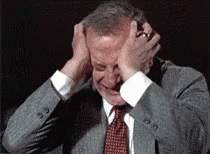 A Man In A Suit And Tie Is Covering His Ears GIF
