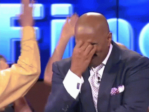 A Man In A Suit And Tie Is Covering His Face GIF