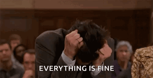 A Man In A Suit And Tie Is Covering His Face With His Hands While A Crowd Watches . GIF