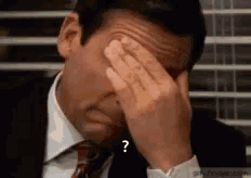A Man In A Suit And Tie Is Covering His Face With His Hands With A Question Mark . GIF