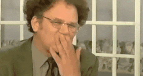 Man In Suit Covering Mouth In Front Of Window GIF