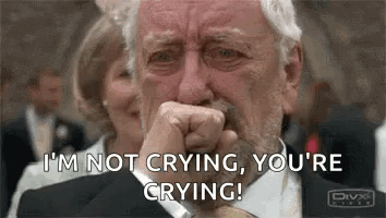 A Man In A Suit And Tie Is Crying While Covering His Mouth With His Hand . GIF