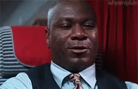 A Man In A Suit And Tie Is Crying While Sitting On An Airplane . GIF