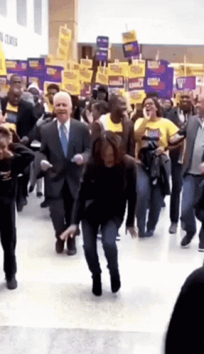 A Man In A Suit And Tie Is Dancing In A Crowd GIF