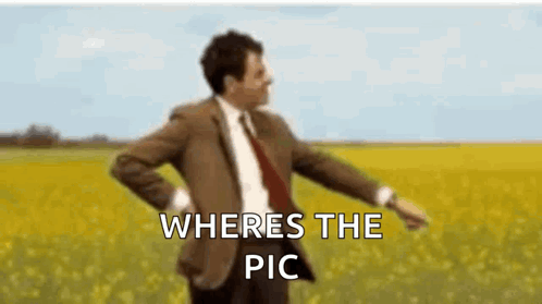 A Man In A Suit And Tie Is Dancing In A Field With The Words `` Where 'S The Pic '' Written Above Him . GIF