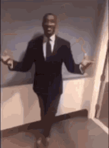 A Man In A Suit And Tie Is Dancing In A Hallway . GIF