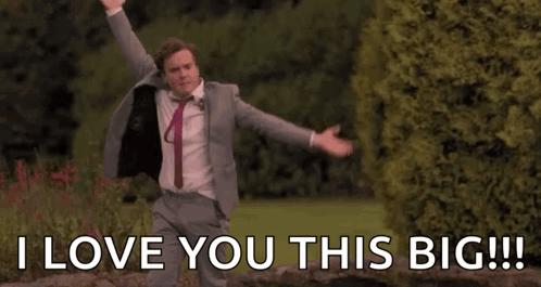 A Man In A Suit And Tie Is Dancing In A Park With His Arms Outstretched . GIF
