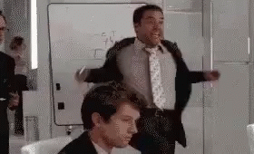 A Man In A Suit And Tie Is Dancing In A Room . GIF