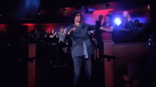 A Man In A Suit And Tie Is Dancing In Front Of A Crowd GIF