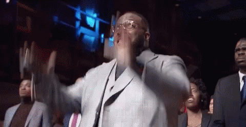 A Man In A Suit And Tie Is Dancing In Front Of A Crowd Of People GIF
