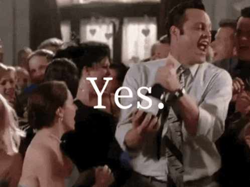 A Man In A Suit And Tie Is Dancing In Front Of A Crowd With The Word Yes Written On The Bottom GIF