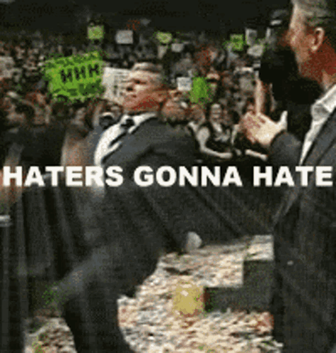 A Man In A Suit And Tie Is Dancing In Front Of A Crowd With The Words Haters Gonna Hate Below Him GIF