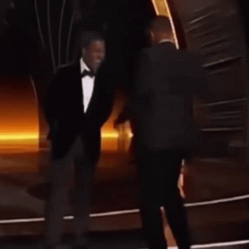 A Man In A Suit And Tie Is Dancing On A Stage . GIF