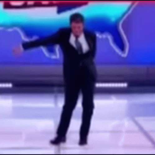 A Man In A Suit And Tie Is Dancing On A Stage In Front Of A Blue Background . GIF