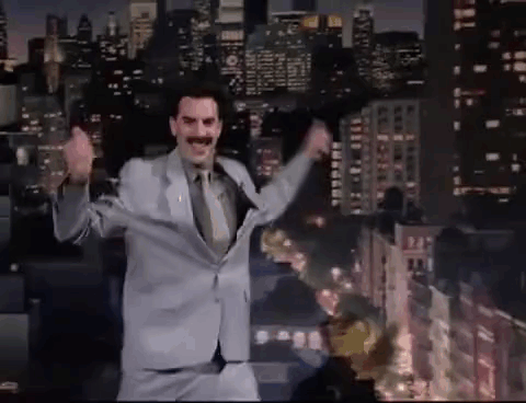 A Man In A Suit And Tie Is Dancing On A Stage In Front Of A City At Night . GIF