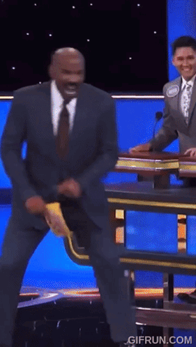 A Man In A Suit And Tie Is Dancing On A Stage With The Website Gifrun.com In The Lower Right Corner GIF