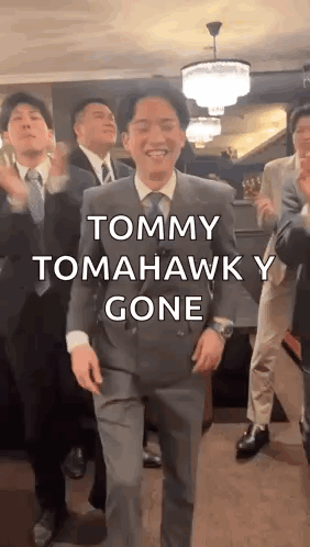 A Man In A Suit And Tie Is Dancing With A Group Of Men . GIF
