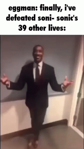 A Man In A Suit And Tie Is Dancing With His Arms Outstretched In A Hallway . GIF