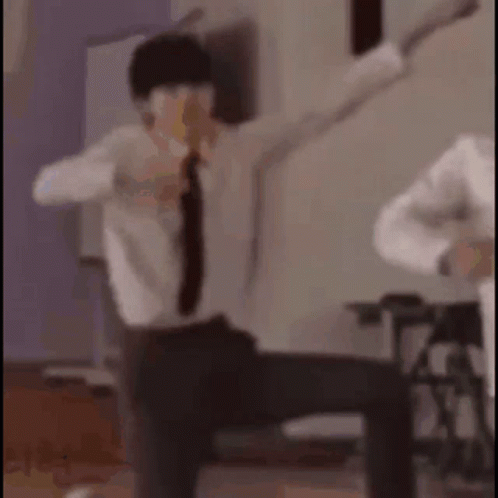 A Man In A Suit And Tie Is Dancing With His Arms Outstretched In A Room . GIF