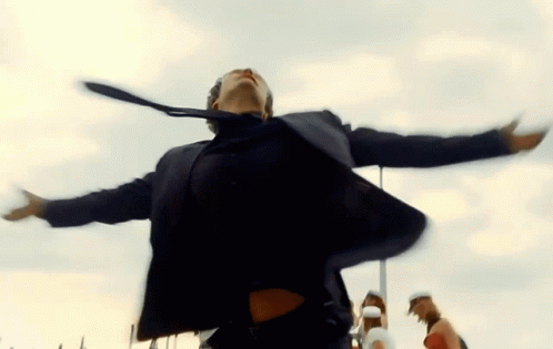 A Man In A Suit And Tie Is Dancing With His Arms Outstretched In The Air GIF