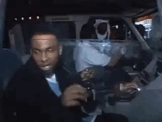 A Man In A Suit And Tie Is Drinking From A Bottle . GIF