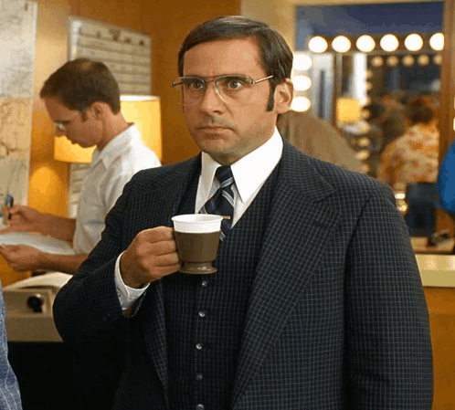 A Man In A Suit And Tie Is Drinking From A Cup GIF