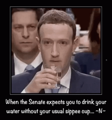 A Man In A Suit And Tie Is Drinking From A Glass . GIF