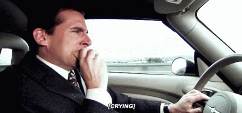 A Man In A Suit And Tie Is Driving A Car While Crying . GIF