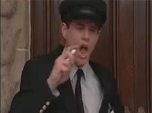 A Man In A Suit And Tie Is Eating A Candy Bar . GIF