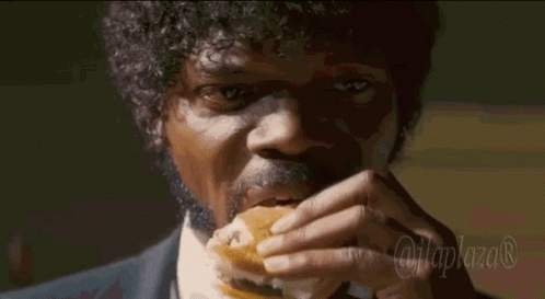 A Man In A Suit And Tie Is Eating A Hamburger With The Hashtag @Laplaza GIF