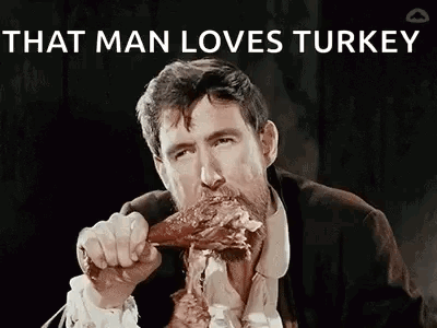 A Man In A Suit And Tie Is Eating A Turkey Leg . GIF