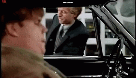 A Man In A Suit And Tie Is Getting Out Of A Car While Another Man Looks On . GIF