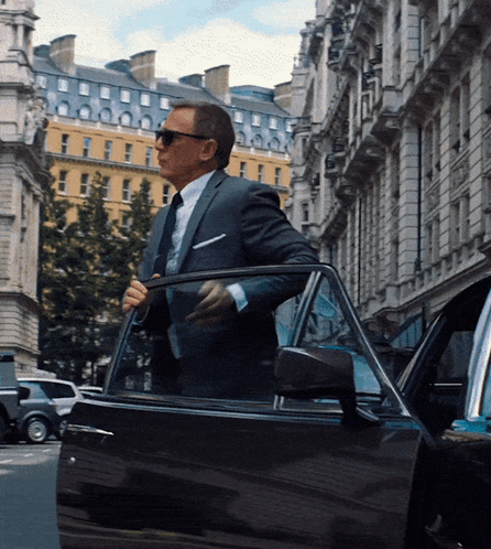 A Man In A Suit And Tie Is Getting Out Of His Car GIF