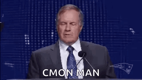 A Man In A Suit And Tie Is Giving A Speech At A Podium With Rings On His Hands . GIF