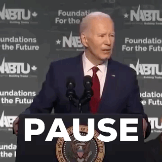 Man In Suit And Tie At Podium With Pause Sign GIF