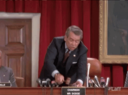 A Man In A Suit And Tie Is Giving A Speech In Front Of A Microphone . GIF