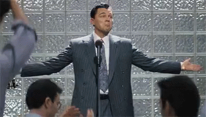 A Man In A Suit And Tie Is Giving A Speech To A Group Of People . GIF