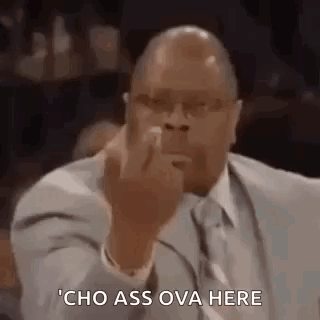 A Man In A Suit And Tie Is Giving The Middle Finger While Sitting In Front Of A Microphone . GIF
