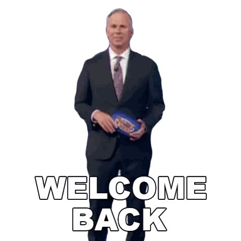 a man in a suit and tie is holding a bag and says welcome back .