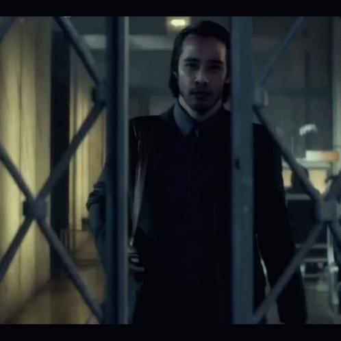 a man in a suit and tie is holding a bloody knife in his hand