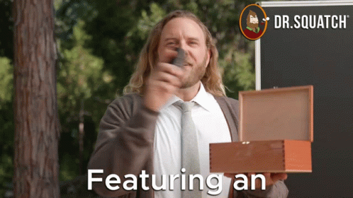 A Man In A Suit And Tie Is Holding A Box That Says Featuring An On It GIF