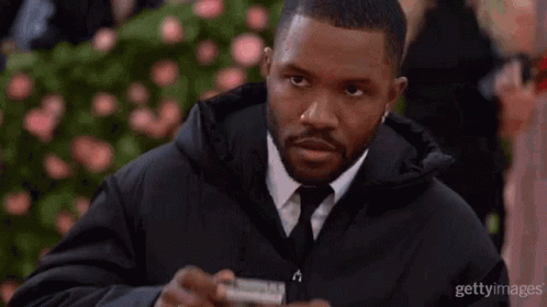 A Man In A Suit And Tie Is Holding A Camera And Looking At It . GIF
