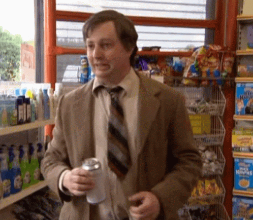 A Man In A Suit And Tie Is Holding A Can Of Soda GIF