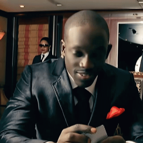 A Man In A Suit And Tie Is Holding A Card GIF