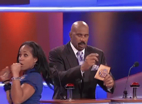 A Man In A Suit And Tie Is Holding A Card That Says ' I 'M Hungry ' On It GIF