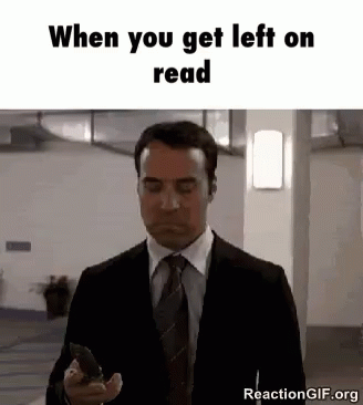A Man In A Suit And Tie Is Holding A Cell Phone And Looking At It . GIF