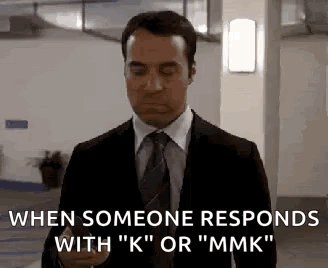 A Man In A Suit And Tie Is Holding A Cell Phone In A Parking Garage . GIF
