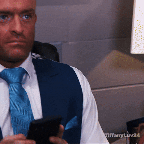 A Man In A Suit And Tie Is Holding A Cell Phone With Tiffany Liv24 Written On The Bottom GIF