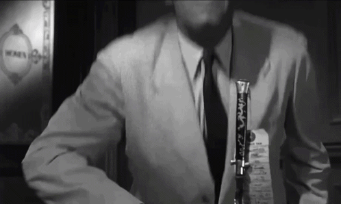 a man in a suit and tie is holding a clarinet